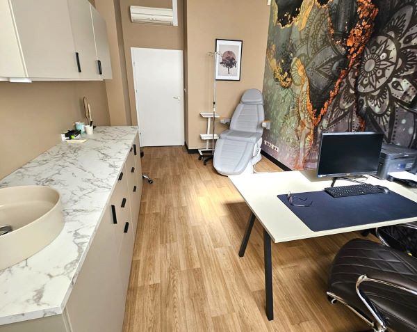 Blat z lewej strony, biurko z prawej strony. Na ścianie kolorowy malunek, oraz fotel z tyłu.