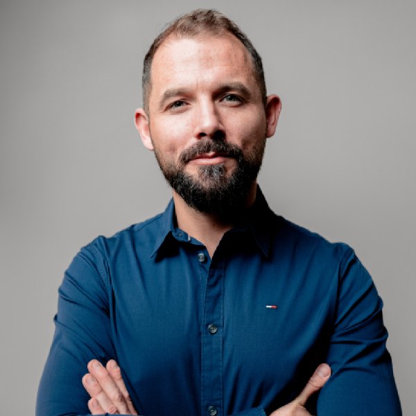 Uśmiechnięty mężczyzna z krótką brodą w szarej koszuli